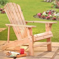 Wooden Adirondack chair with slatted back and wide armrests on a patio, surrounded by grass and flowers.