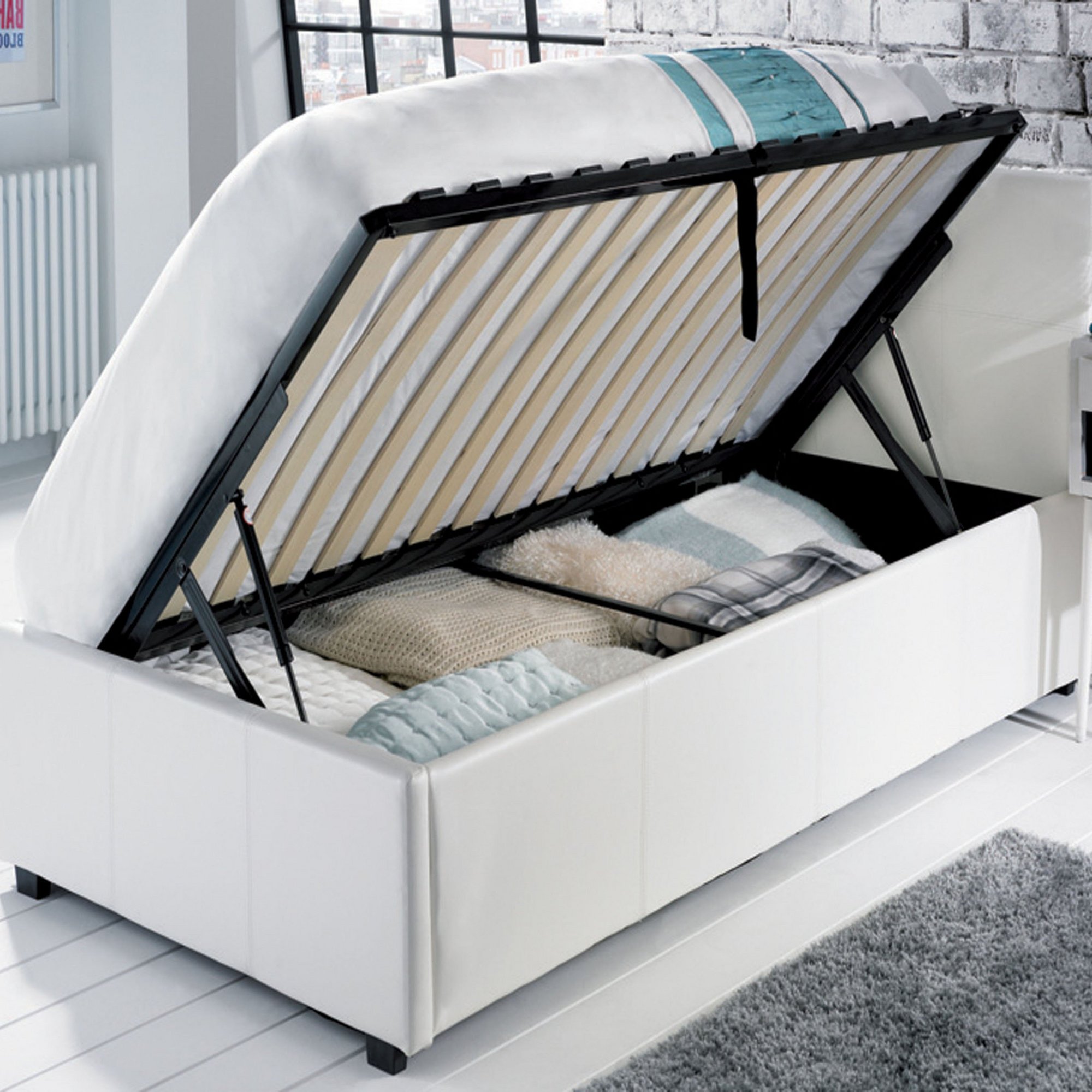 White PU upholstered bed with a side lift ottoman feature, revealing storage space underneath, accompanied by a bonnel mattress and a textured bedding set.