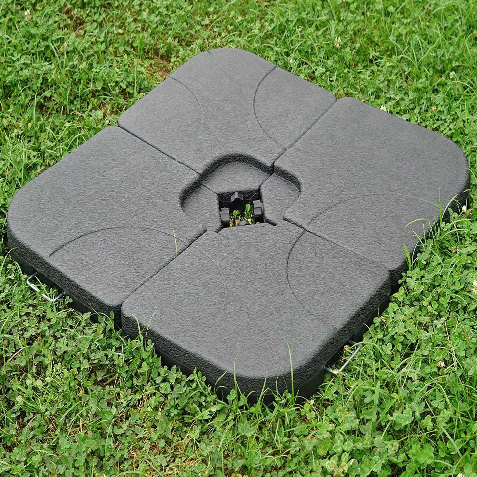 Four black, square patio umbrella base weights made of durable plastic, featuring a central connector and a textured surface, placed on green grass.