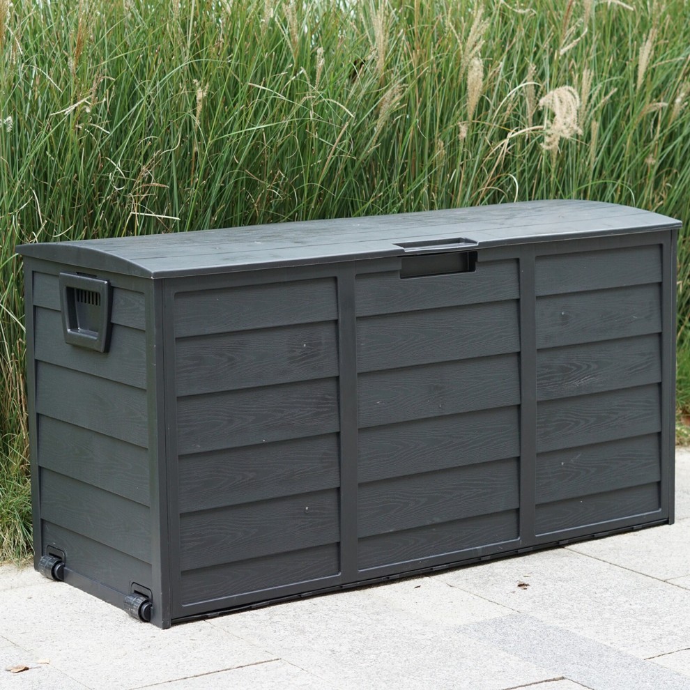 Black plastic storage box with a 300L capacity, featuring a textured surface, a hinged lid, and wheels for easy mobility, set against a backdrop of tall grass.