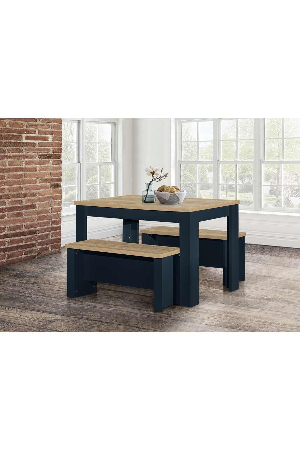 Traditional dining table and bench set in dark navy with a natural wood top, featuring a sturdy design and minimalist style, set against a brick wall and large windows.