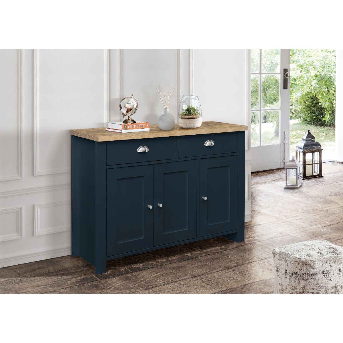 Navy blue sideboard with oak top, featuring three doors and two drawers, set against a bright room with natural light and decorative items on top.