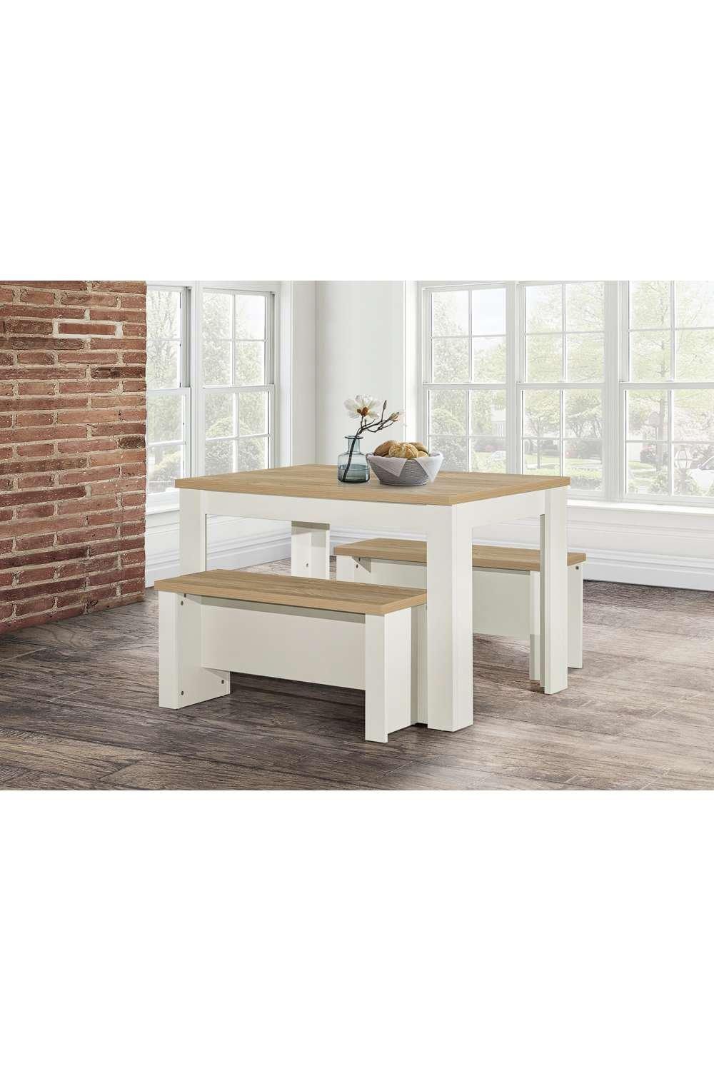 Cream-colored wooden dining table and bench set with a natural wood top, featuring a traditional design and sturdy rectangular legs, positioned in a bright, airy room.