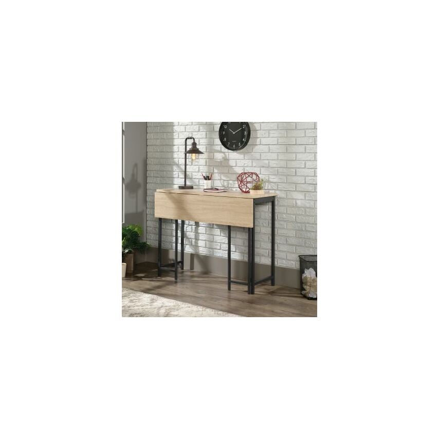 Industrial-style high work table featuring a light wood finish with a flip extension, supported by a sturdy black metal frame, set against a white brick wall.