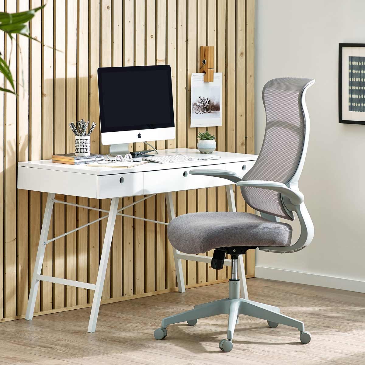 Stylish office chair with a light grey fabric seat and backrest, featuring a sleek white frame and five caster wheels, positioned next to a modern desk and computer setup.