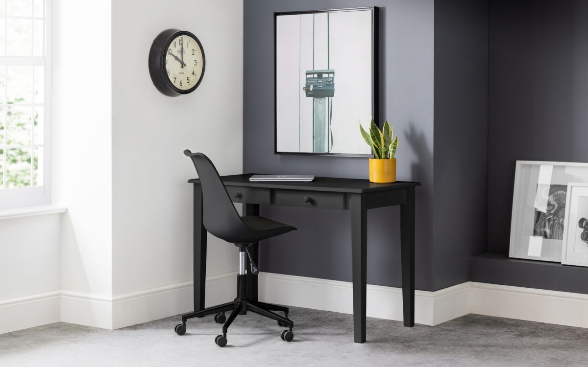 Black ergonomic office chair with a curved backrest and adjustable height, positioned next to a sleek black desk in a modern workspace featuring a clock and potted plant.