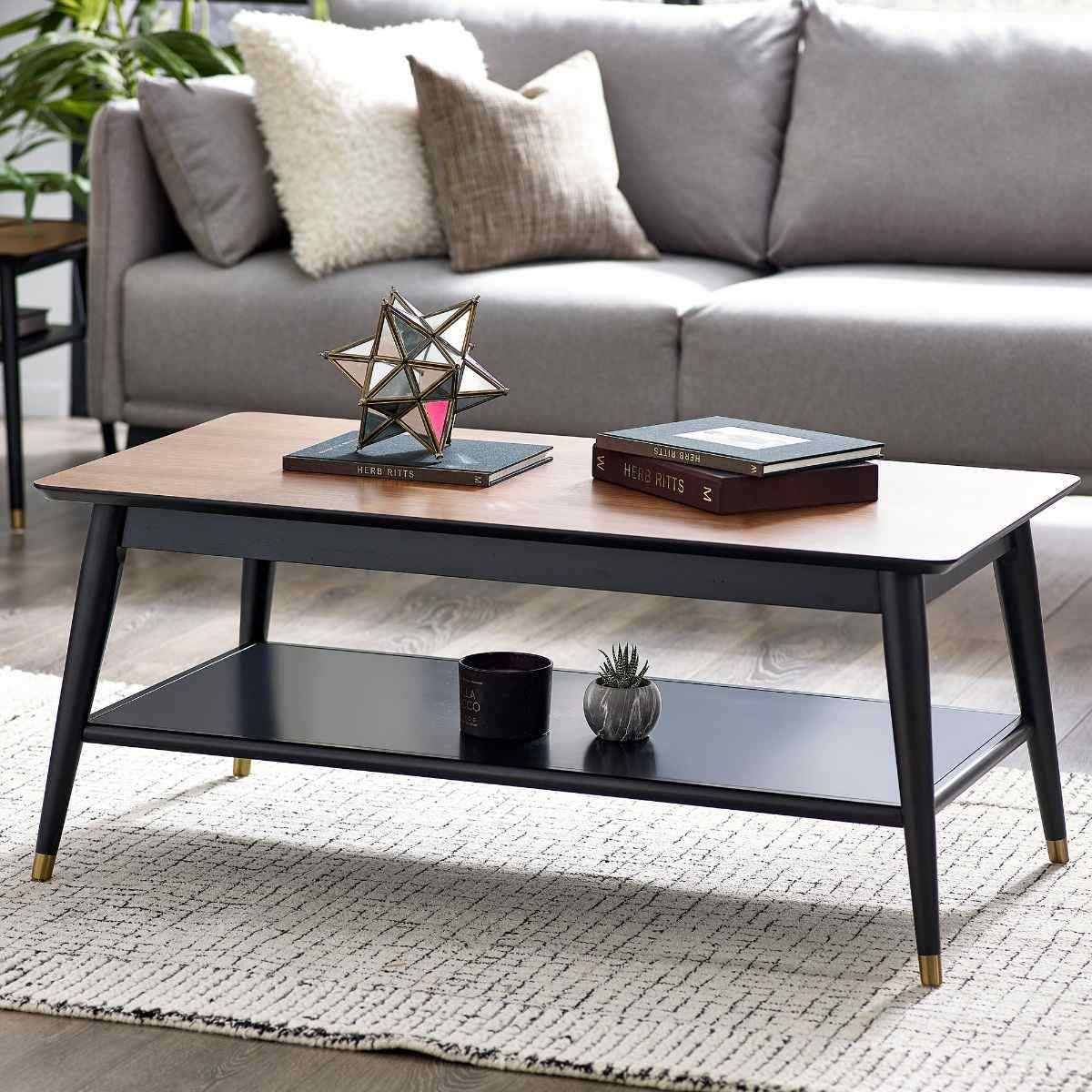 Walnut and black coffee table featuring a sleek design, a spacious top surface, a lower shelf for storage, and stylish gold-tipped legs, ideal for modern living spaces.