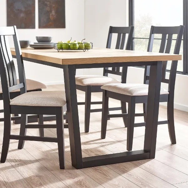 Julian Bowen Hilton Dining Table features a light oak top with a sleek black metal frame, accompanied by four matching chairs with beige upholstered seats.