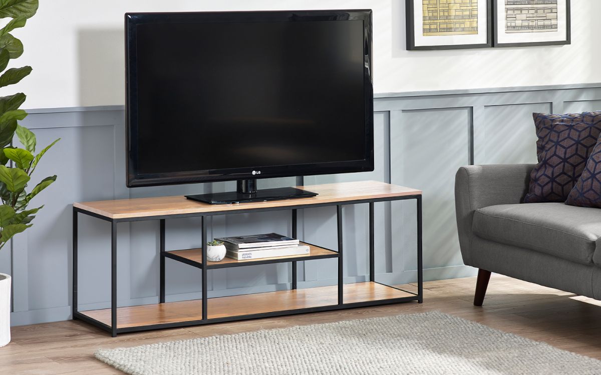 Sonoma oak TV unit with a sleek brown finish, featuring a black metal frame, two open shelves, and a spacious top for a television, set against a light gray wall.