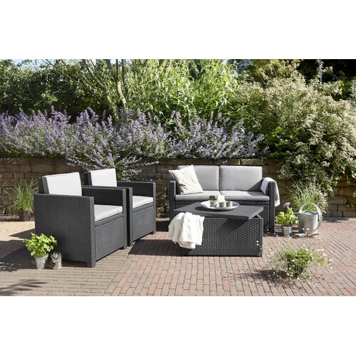 Grey Keter Armona 4-seat outdoor sofa set featuring a sleek design with woven rattan texture, plush grey cushions, and a matching coffee table, surrounded by lush greenery.