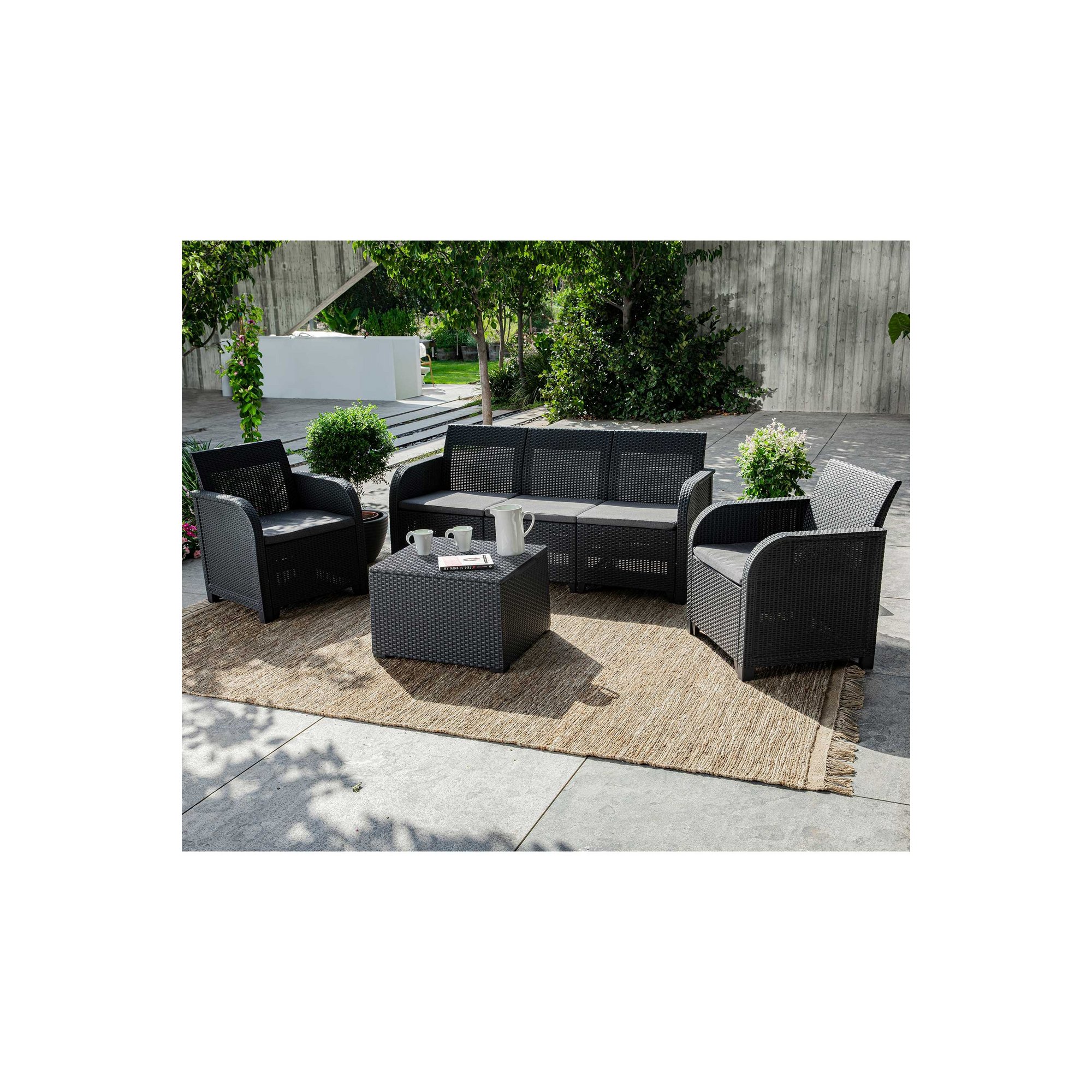 Grey Keter Rosalie 3-seat set with large table, featuring wicker-style design, plush cushions, and a modern aesthetic, arranged on a natural fiber rug in an outdoor setting.