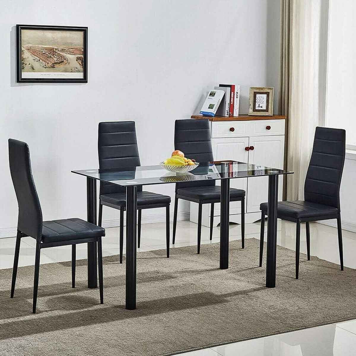 Black glass dining table with four matching leather chairs, featuring a sleek design and modern aesthetic, set on a light-colored rug in a bright room.