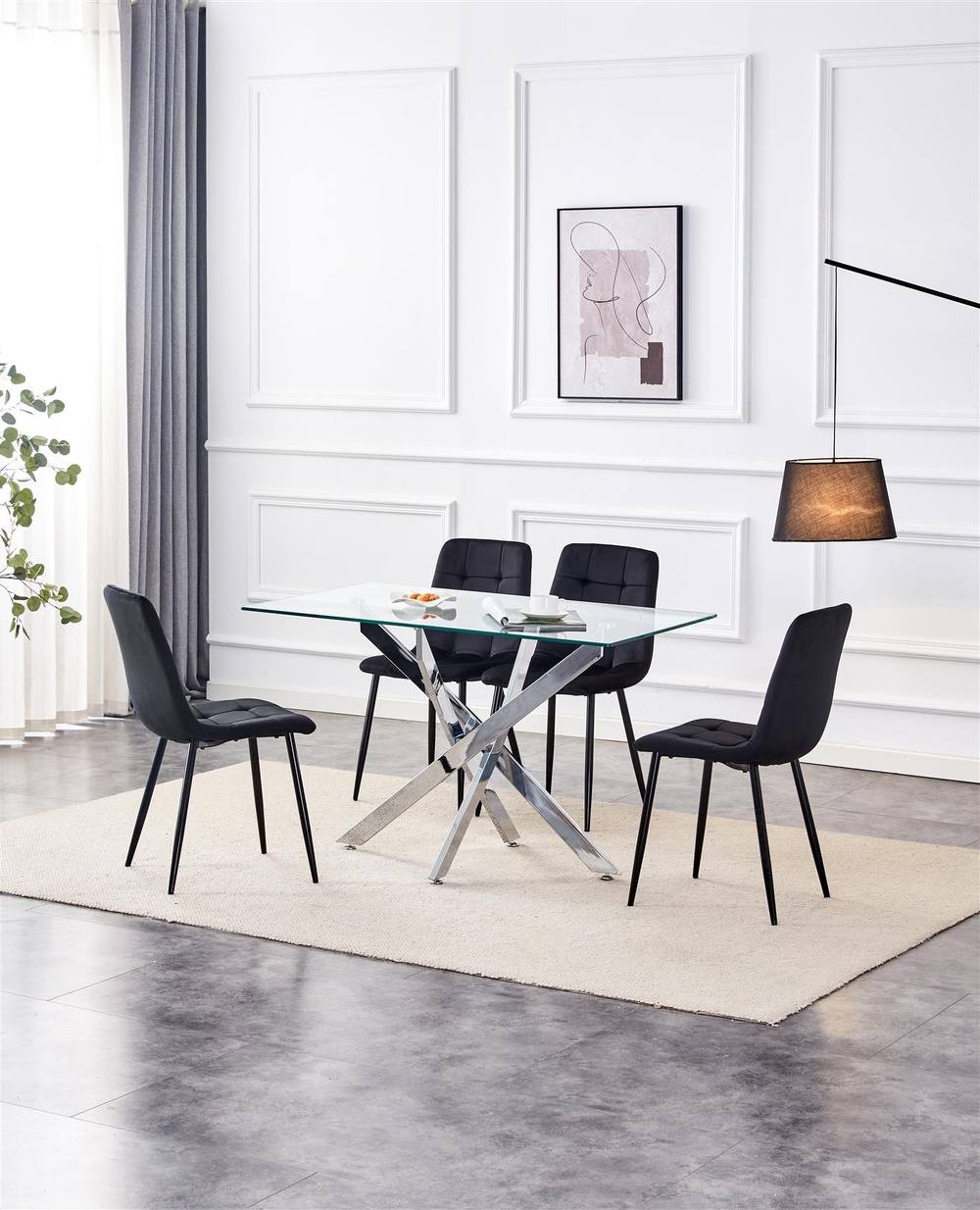 Rectangle glass dining table with a sleek silver base, accompanied by four black velvet chairs, set on a light rug in a modern, well-lit room.
