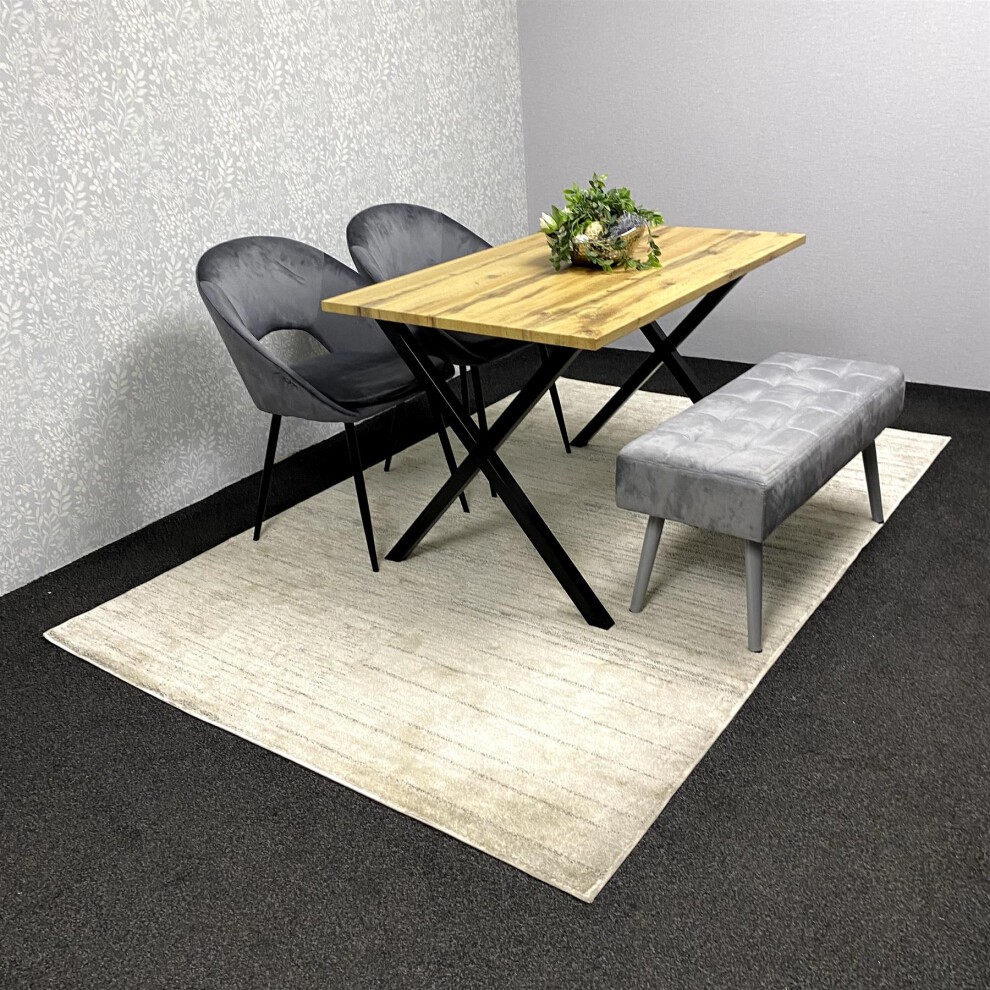 Grey wooden dining table set featuring a natural wood top, black metal legs, two grey upholstered chairs, and a grey tufted bench, all on a light rug in a minimalistic setting.