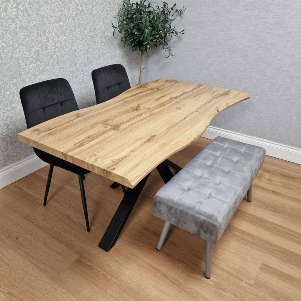 Kosy Koala dining set featuring a natural wood table with a live edge, black velvet chairs, and a tufted grey bench with metal legs, set against a textured wall.