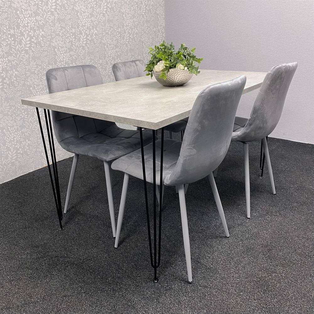 Modern grey dining table with a smooth surface and black metal legs, accompanied by four grey velvet chairs featuring sleek, tapered legs and a minimalist design.
