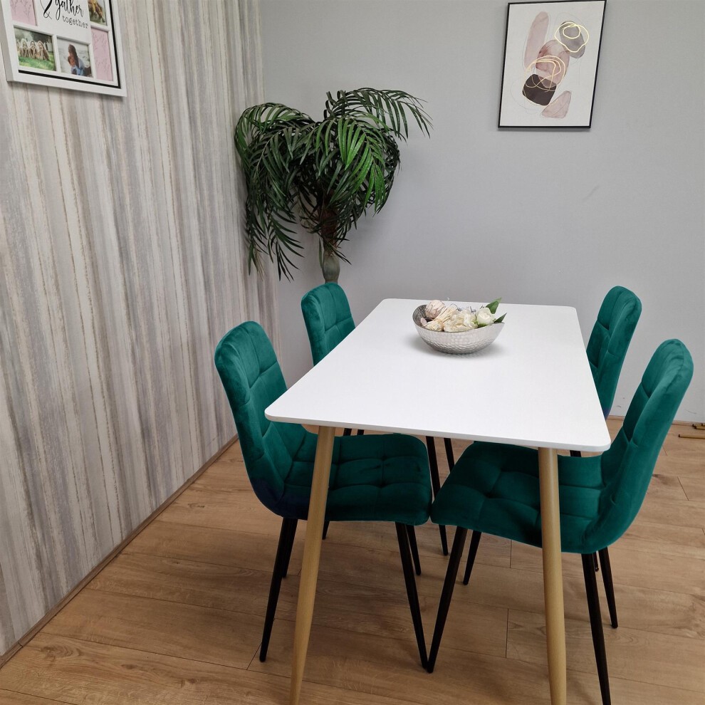 Modern grey dining table with two green upholstered benches, featuring a minimalist design and wooden legs, set against a light-colored wall with decorative accents.