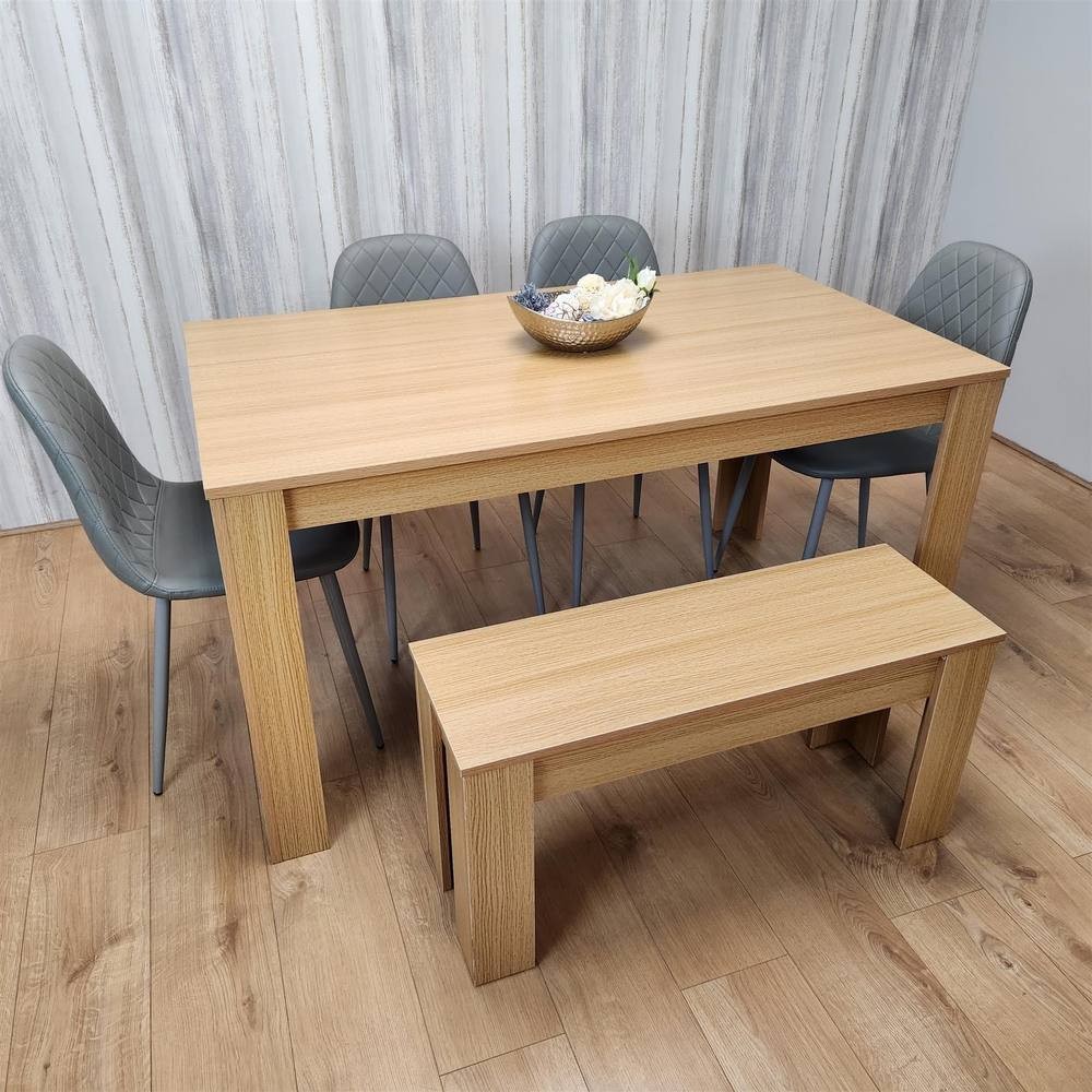 KOSY KOALA wooden dining table set featuring an oak effect table, four grey gem-patterned chairs, and a beige bench, all set against a light wood backdrop.