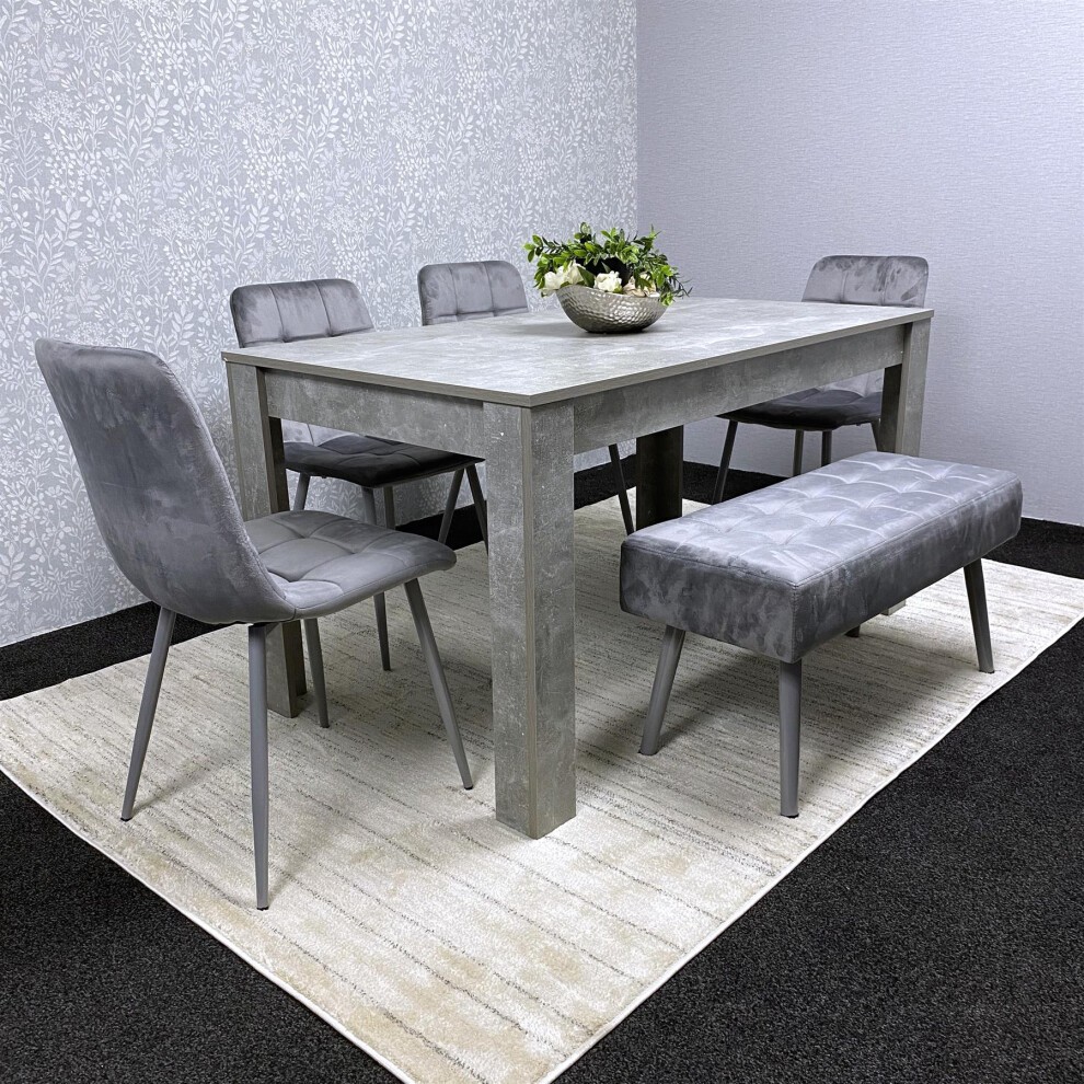 Kosy Koala dining set featuring a light grey table with reinforced wooden legs, complemented by soft velvet chairs and a tufted bench, all set on a neutral rug.