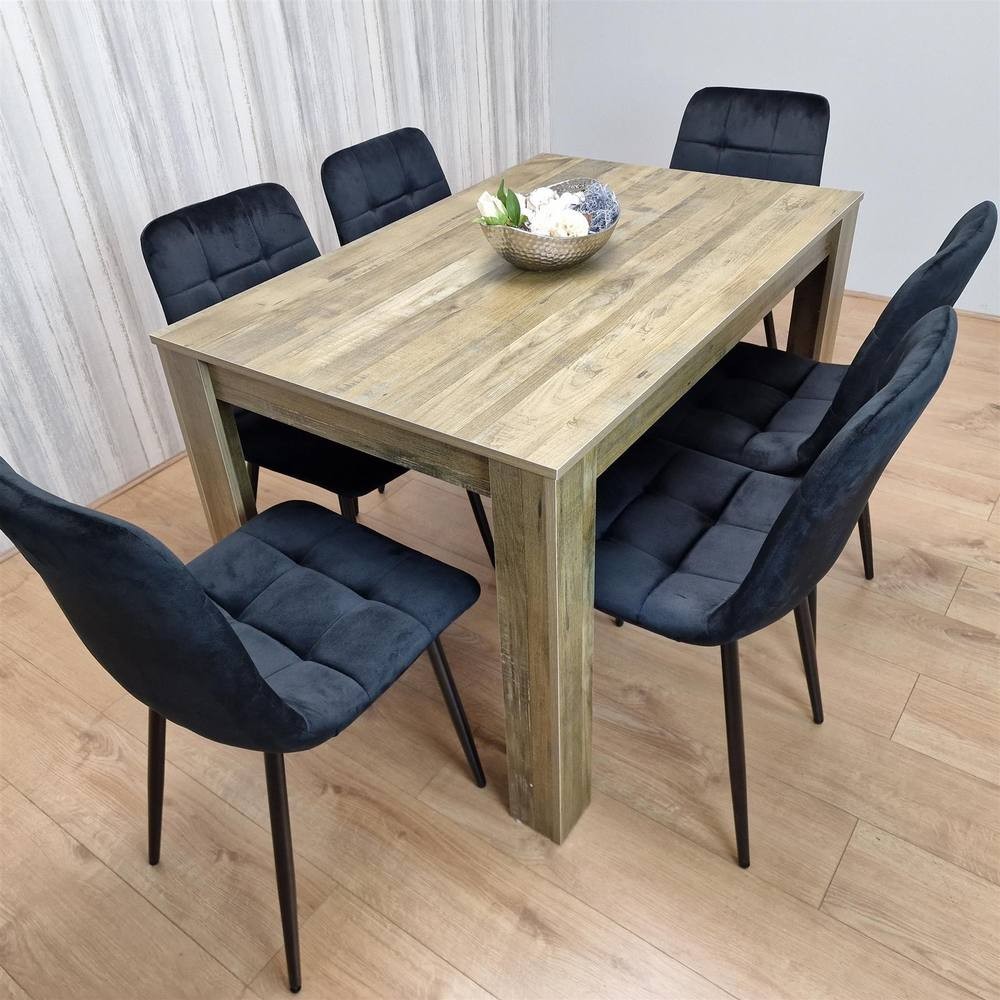Rustic wood dining table in brown with a textured finish, accompanied by six black velvet chairs featuring tufted upholstery and slender black legs.