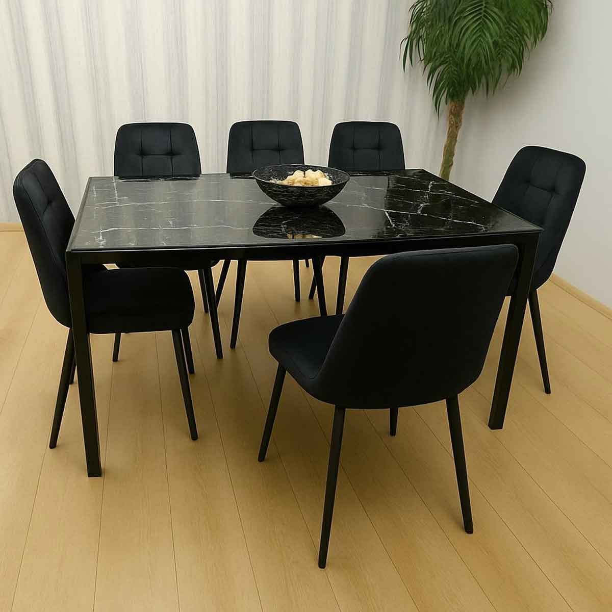 Black glass dining table with a marble effect, surrounded by six velvet chairs, all featuring sleek black upholstery and modern design, set against a light wooden floor and subtle greenery.
