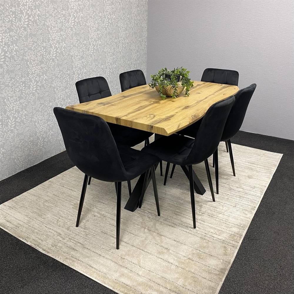 Stylish brown wooden dining table with a natural finish, accompanied by six black velvet chairs, set on a light rug against a textured wall.