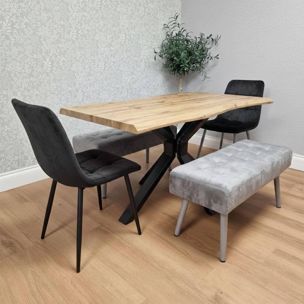 Kosy Koala wooden dining table with a natural wood finish, two black upholstered chairs, and two grey tufted benches, set against a light grey wall and wooden floor.