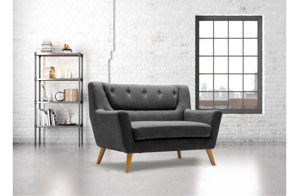 Grey fabric 2-seater sofa with a modern retro design, featuring wood legs and button-tufted backrest, set against a bright, airy room with a large window and bookshelf.