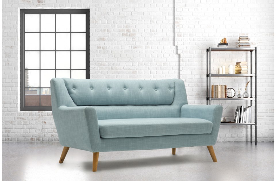 Modern retro-style 3-seater sofa in light blue fabric with wood legs, featuring button detailing on the backrest, set against a bright, minimalist interior.