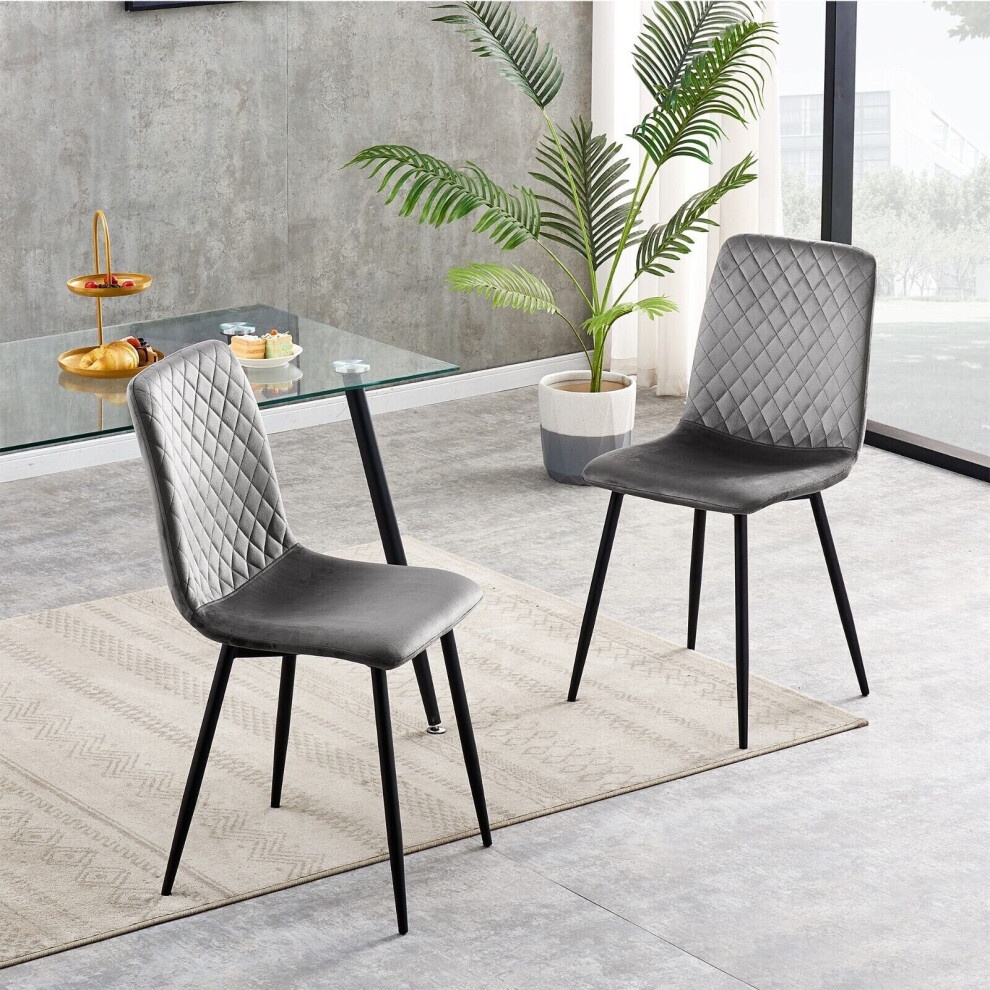 Set of 2 dark grey velvet dining chairs with diamond-patterned upholstery and sleek black legs, placed on a light rug in a modern interior setting.