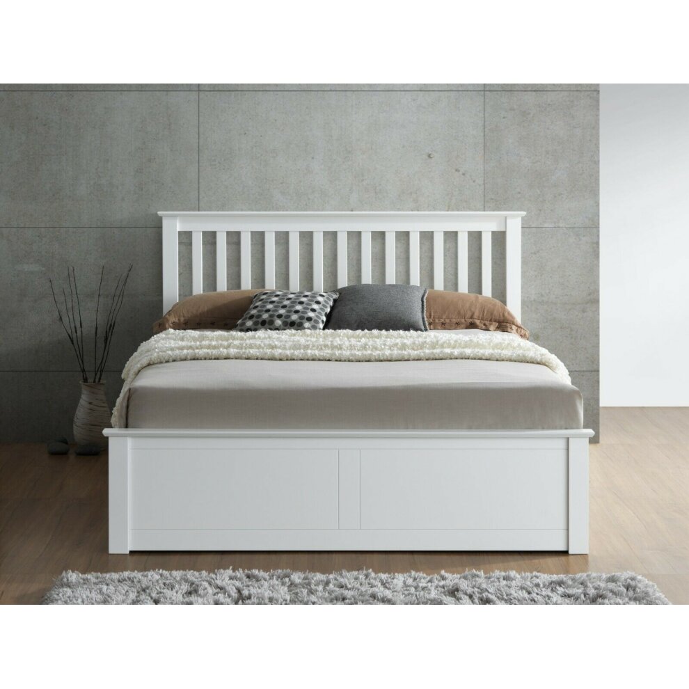 White wooden double ottoman bed with a slatted headboard, featuring a spacious storage compartment and styled with neutral bedding and decorative pillows.