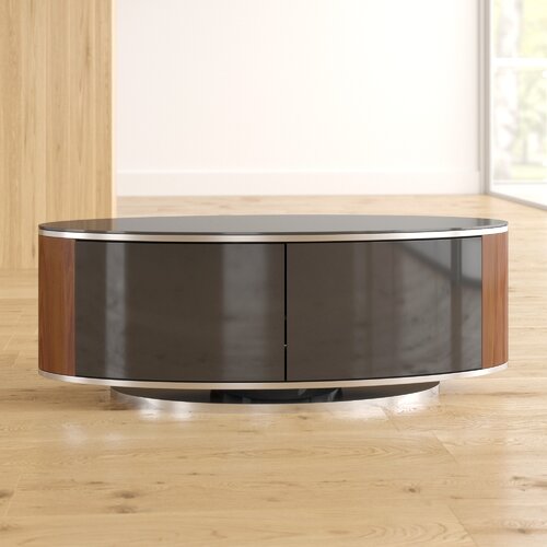 Oval coffee table featuring a high gloss black top, walnut wood sides, and a sleek chrome base, set against a light wooden floor and bright interior.