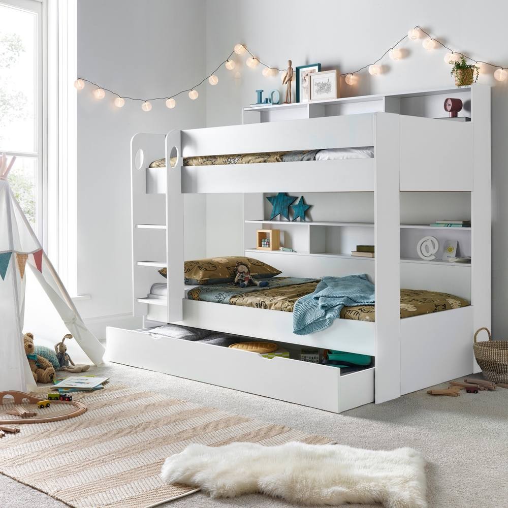 White wooden bunk bed with a built-in storage drawer, featuring pocket mattresses and shelves, set in a bright room with decorative fairy lights and a cozy rug.