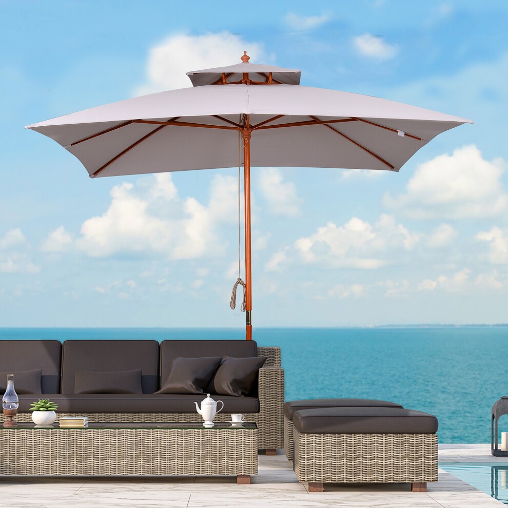 Grey square parasol with a wooden frame and a central pole, featuring a vented canopy, positioned over a modern outdoor seating area by the sea.