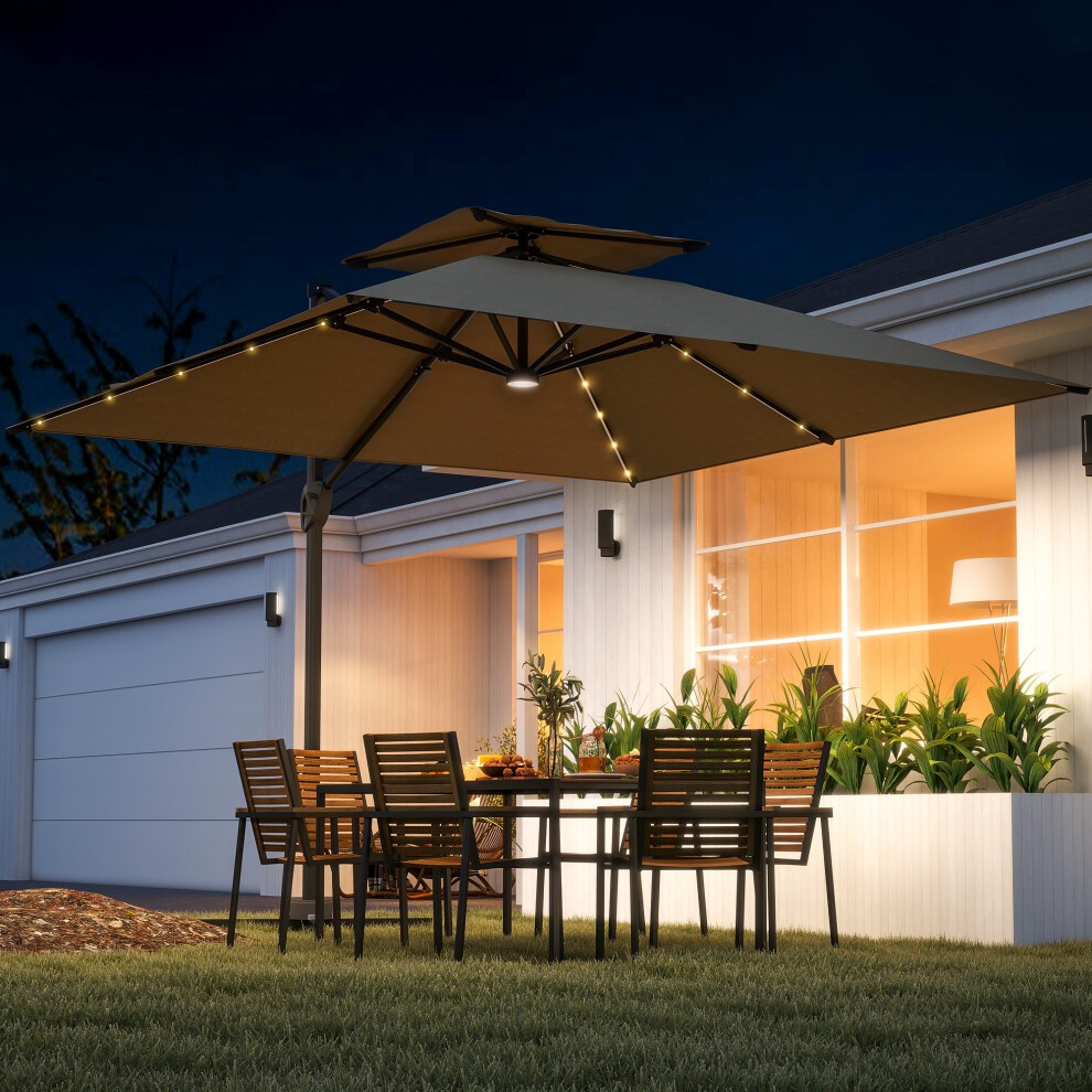 3.5m khaki and brown aluminium cantilever parasol with LED lights, featuring a crank and tilt mechanism, set over a dining table with wooden chairs in a garden at night.