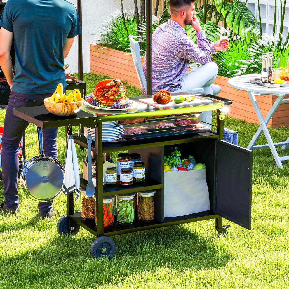 Stainless steel outdoor BBQ trolley in black with a folding side table, featuring storage shelves, wheels for mobility, and a variety of food items displayed on top.