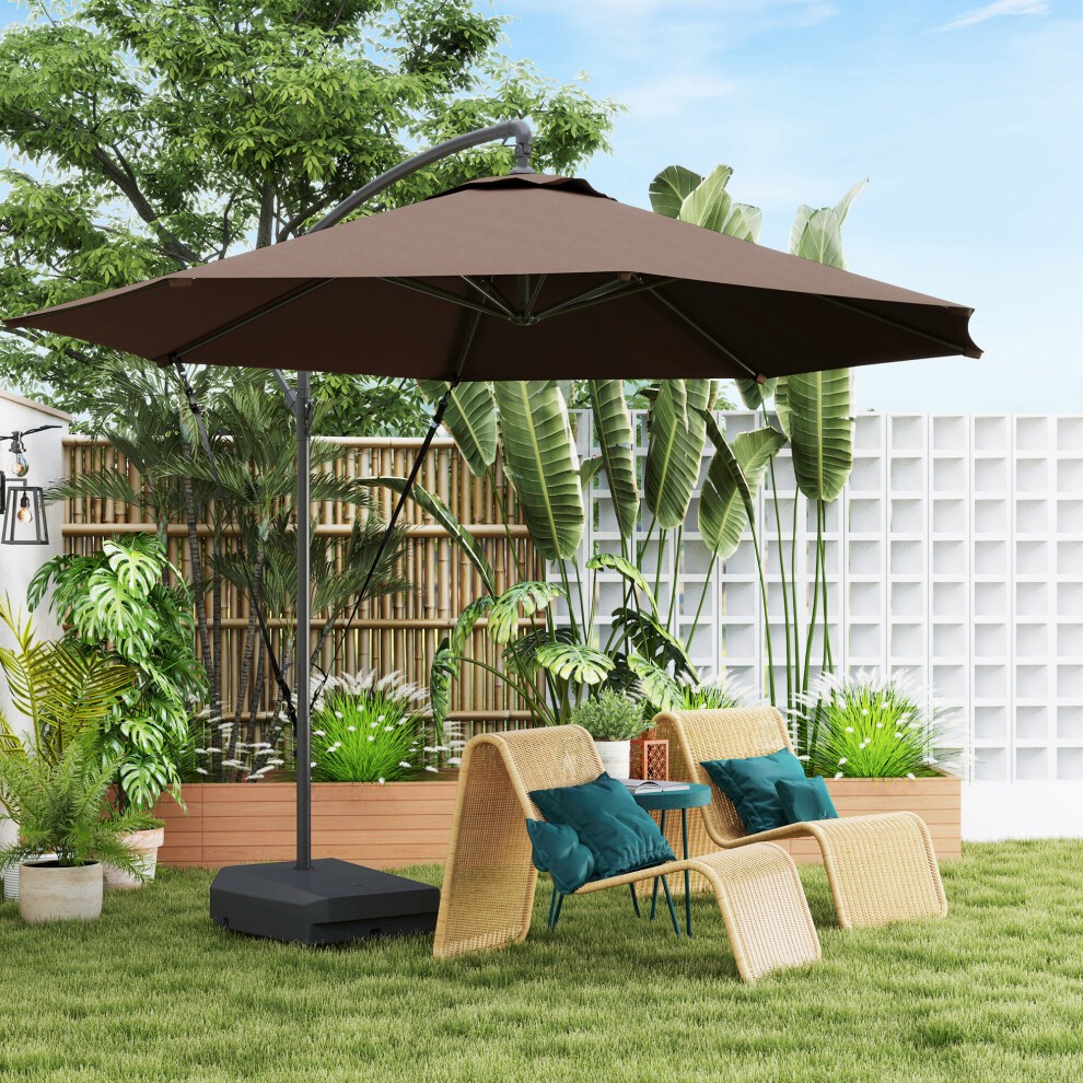 Brown cantilever parasol with a weighted base and wind strap, set in a garden with green plants, two wicker chairs, and blue cushions against a light backdrop.