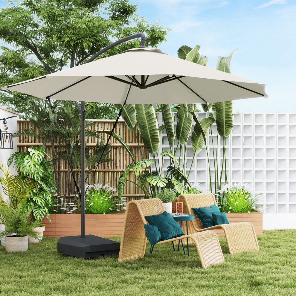 Cream-colored cantilever parasol with a weighted base and wind strap, set in a lush garden with bamboo fencing and rattan chairs featuring teal cushions.