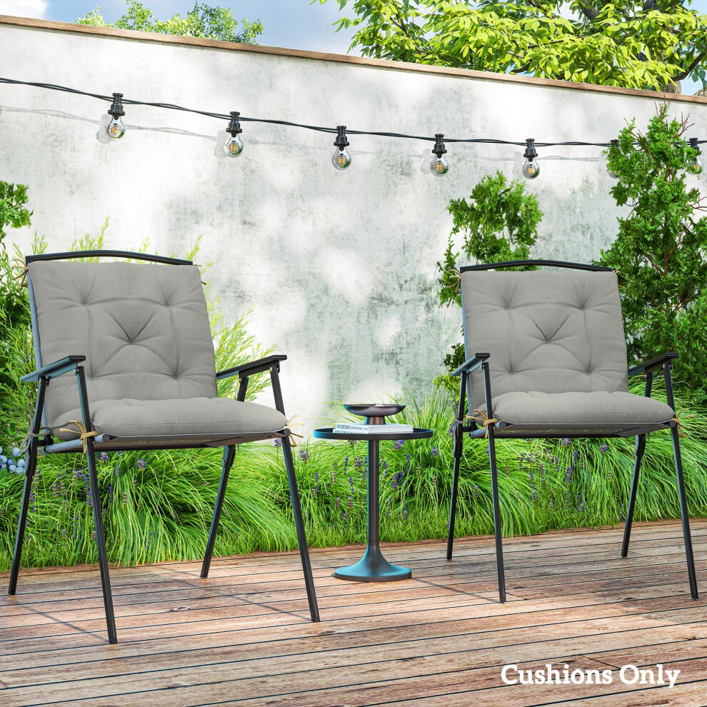 Set of 2 light gray garden chair cushions with tufted design, made for outdoor and indoor use, placed on a wooden deck with greenery and string lights in the background.