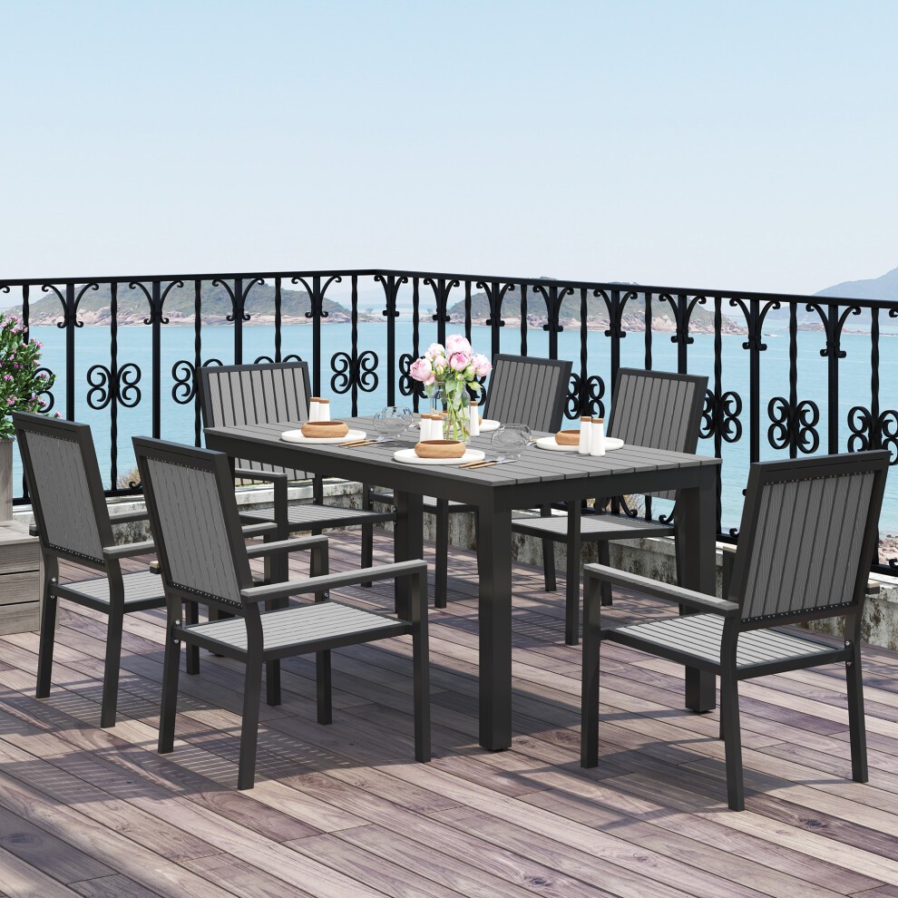 Grey aluminium garden dining set for six, featuring a rectangular table and stackable chairs with slatted backs, set on a wooden deck overlooking a scenic water view.