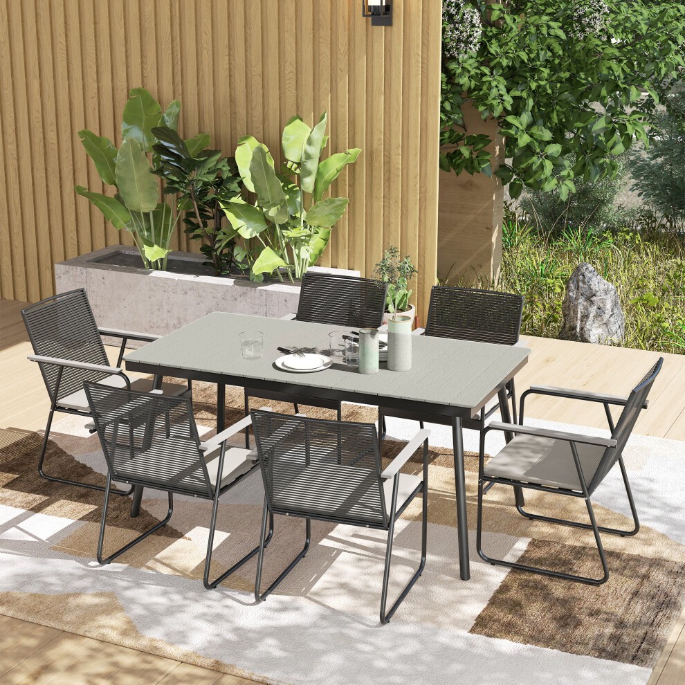 Grey rattan garden dining set for six, featuring cushioned seats and a rectangular table, set on a wooden deck surrounded by greenery and decorative plants.