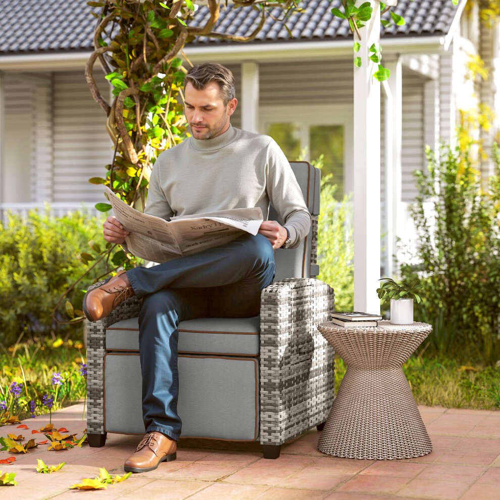 Rattan garden recliner sun lounger in mixed grey with a flip table, featuring a comfortable padded seat and stylish woven design, set in a lush outdoor environment.