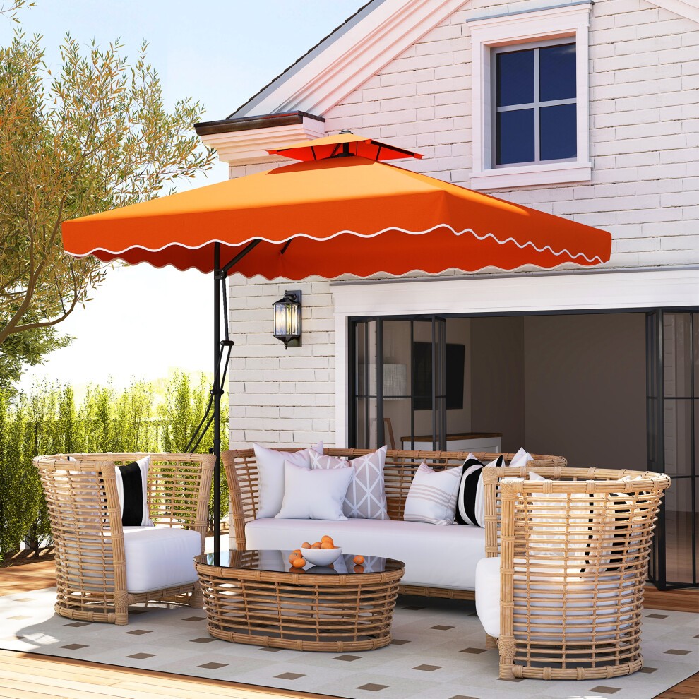 Orange cantilever garden parasol umbrella with a scalloped edge and cross base, set above a rattan seating area on a patio, surrounded by greenery and a white brick house.