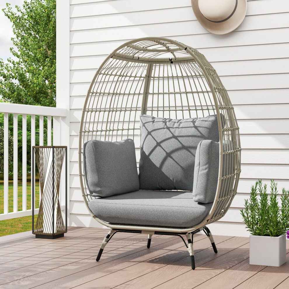 Charcoal grey PE rattan egg chair with padded grey cushions, featuring a woven design and sturdy black legs, set against a bright outdoor backdrop.
