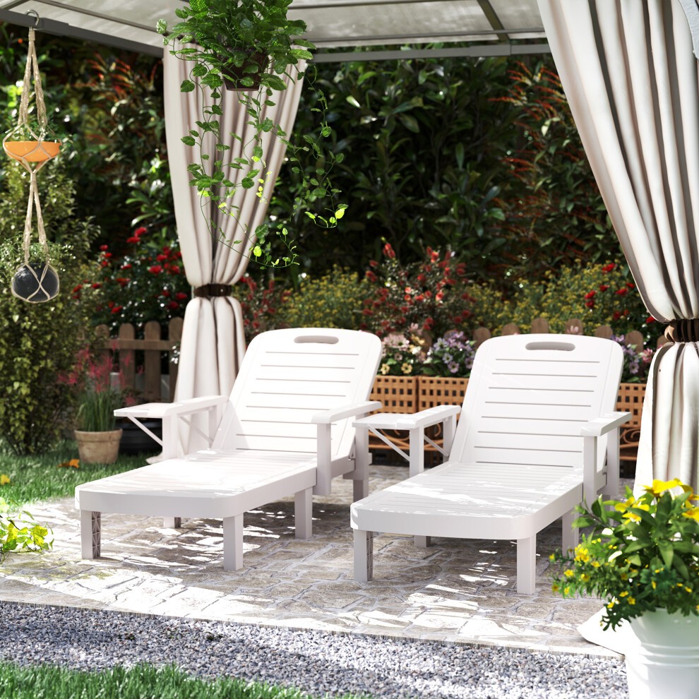 Set of 2 white resin reclining sun loungers with slatted design, positioned under a canopy in a garden setting, surrounded by greenery and decorative plants.