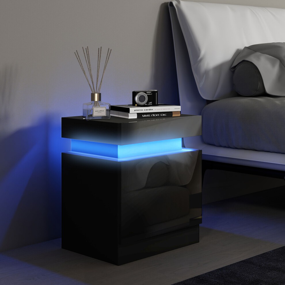 High gloss black bedside table featuring two drawers, illuminated with blue LED light, styled with decorative items on top, positioned next to a bed.