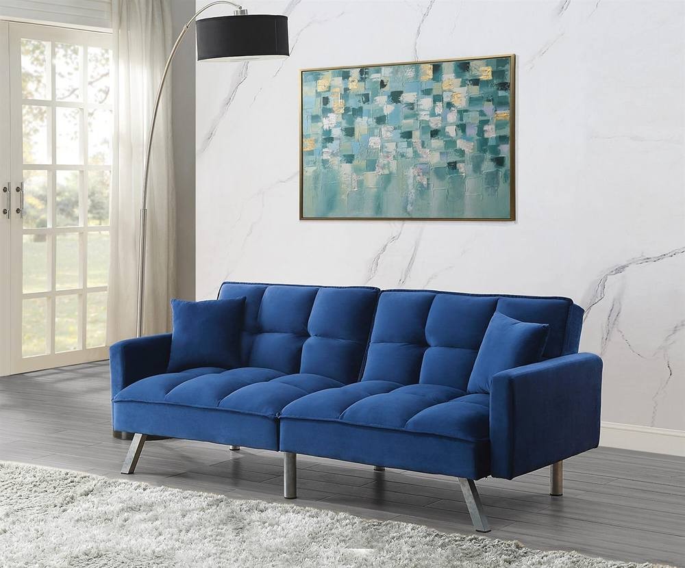 Blue velvet 2-seater sofa bed with a click-clack mechanism, featuring tufted cushions, two matching pillows, and sleek metal legs, set against a light, modern interior.