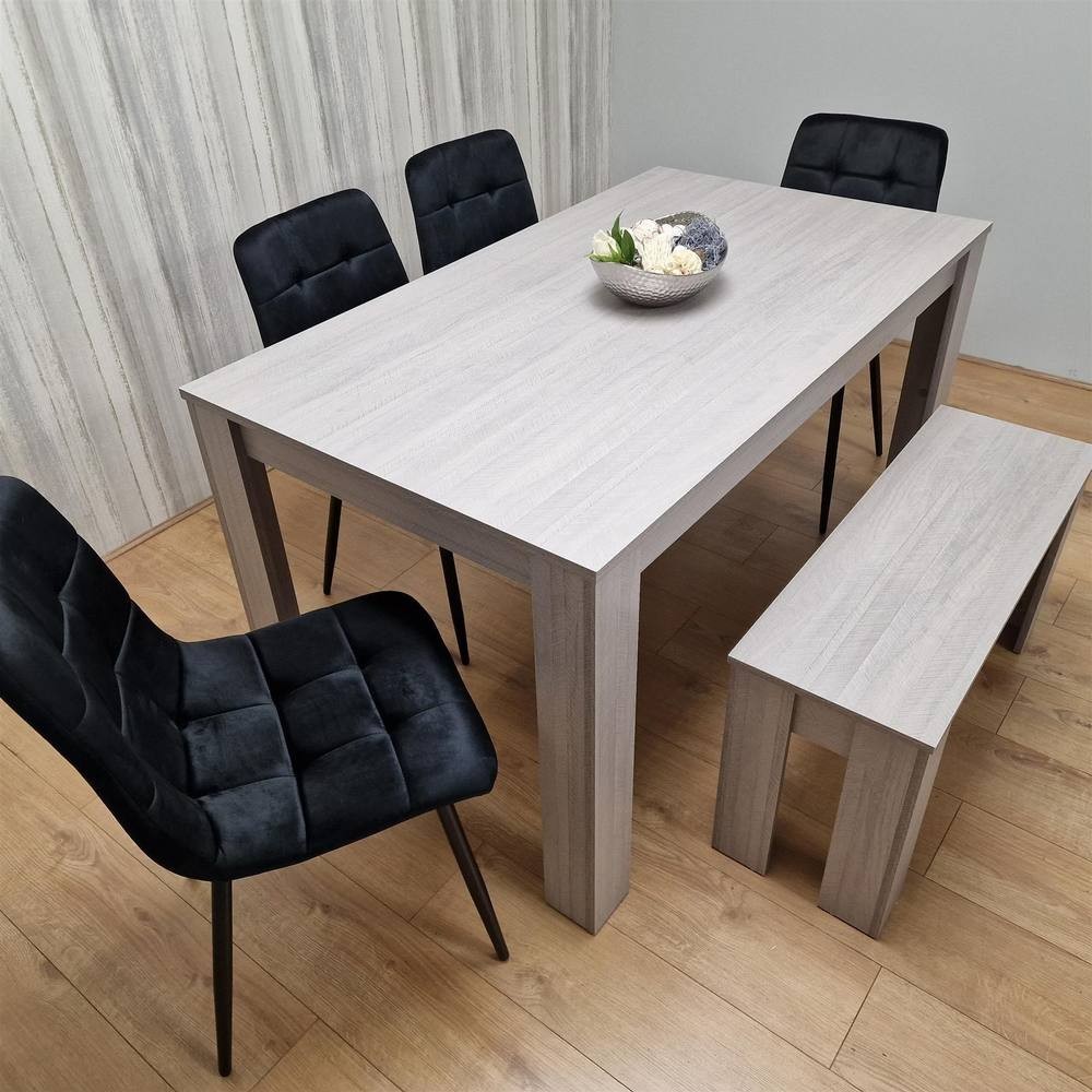 Grey dining table set featuring a rectangular table, four black velvet chairs with tufted backs, and a matching bench, all set on a wooden floor with a decorative bowl on the table.