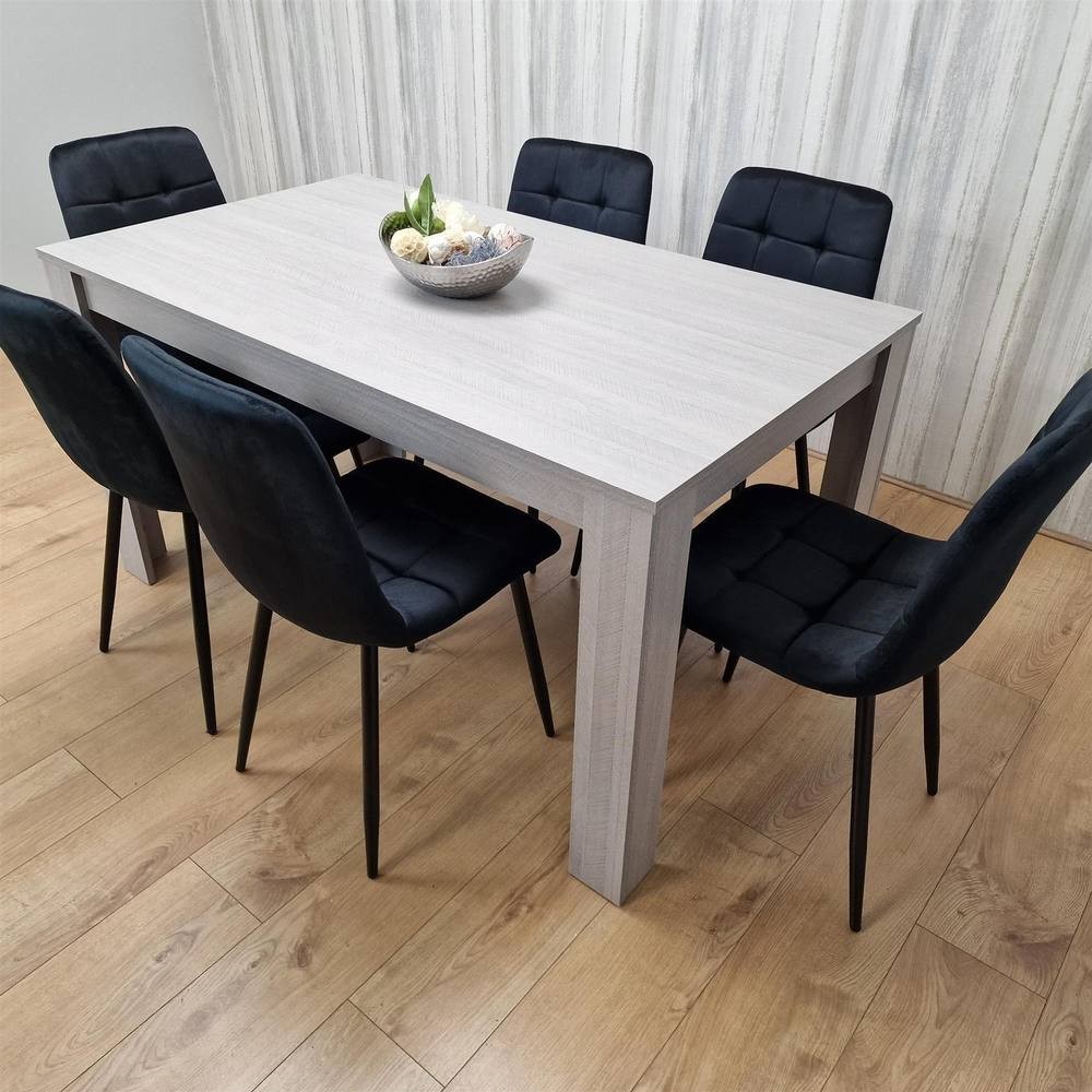 Grey dining table set featuring a rectangular table with a textured finish and six black velvet chairs with tufted backs, set on a wooden floor.