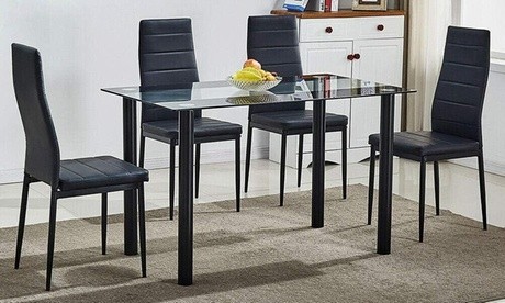 Black dining table with clear glass top, accompanied by six black velvet chairs featuring a sleek, modern design, set on a light-colored rug in a bright room.